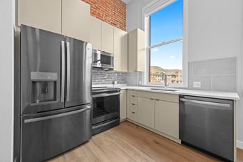 A modern kitchen with stainless steel appliances and a brick accent wall.